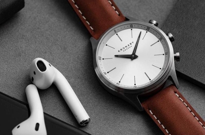 Kronaby Hybrid Smartwatch neben Bluetooth Kopfhörern