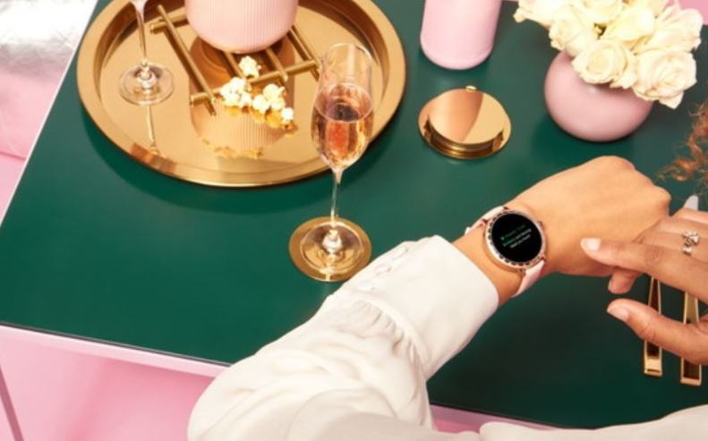 Frau beim feierlich gedeckten Tisch mit Kate Spade New York Scallop 2 Smartwatch am Handgelenk